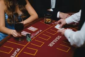 Pilih meja — lihat nama dealer, batas taruhan minimum dan maksimum, dan jumlah pemain aktif. Menu pemilihan permainan Table Games menampilkan berbagai meja dengan dealer dan batas taruhan